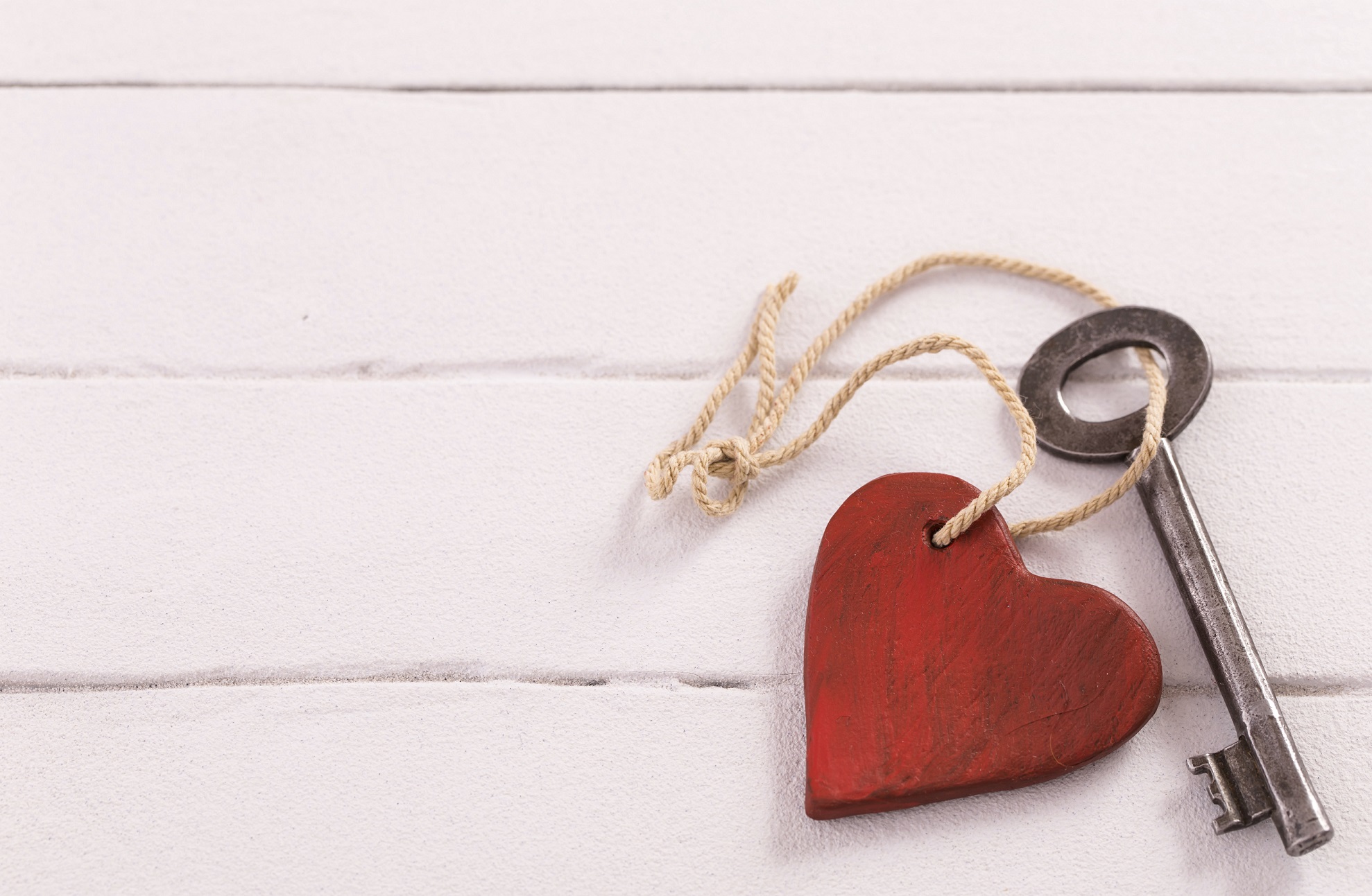 Old  key with a heart on white wood