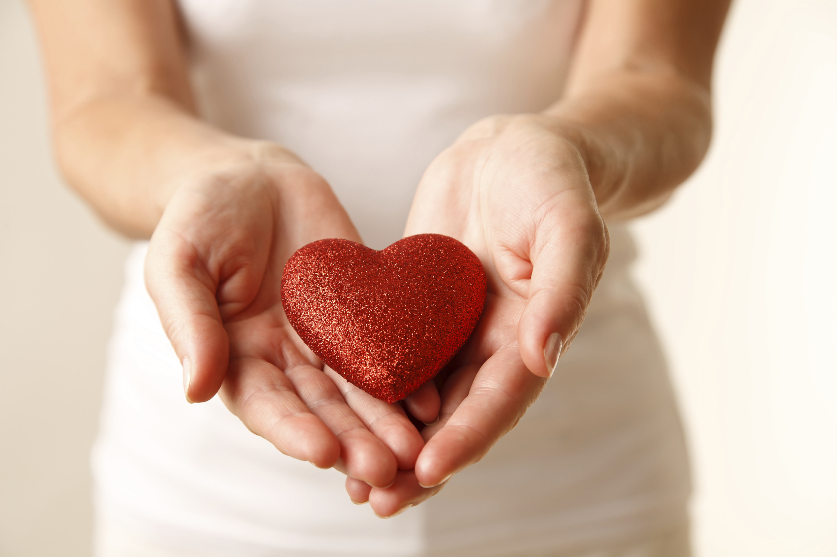 Giving love concept with hands holding a red heart.